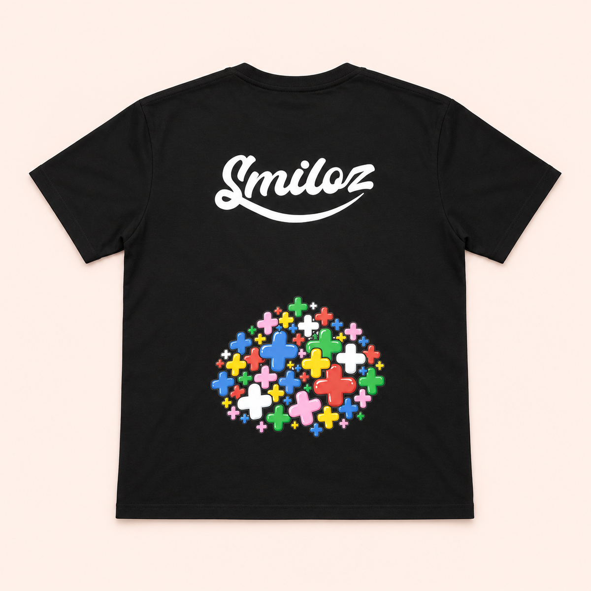 Back of black Smiloz T-shirt with large white logo and lower multicolour plus-sign print on a blush background