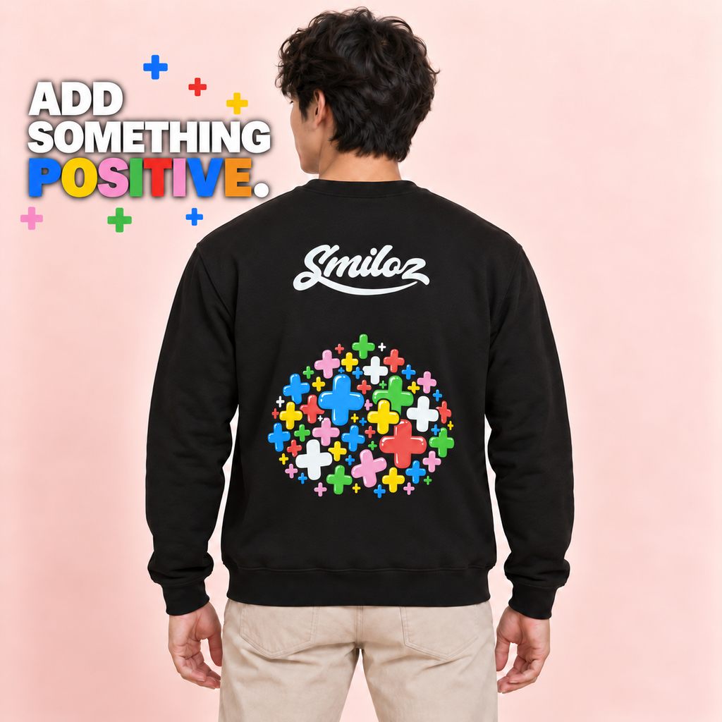 Back view of model wearing the black Smiloz Multicolour Plus signs jumper with Add Something Positive campaign slogan