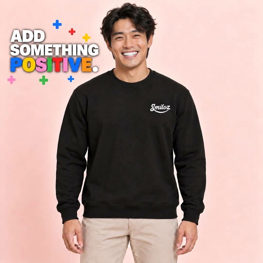 Smiling front-facing model wearing the black Smiloz Multicolour Plus signs jumper with Add Something Positive slogan